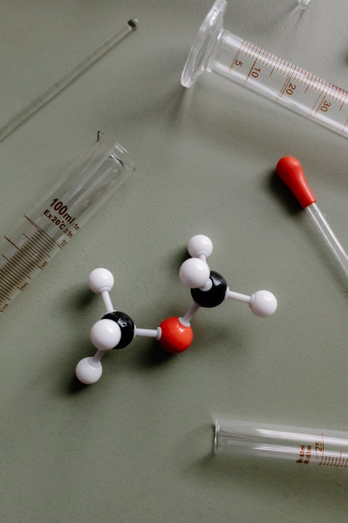 Close-up of a molecular model surrounded by laboratory equipment like pipettes and test tubes.